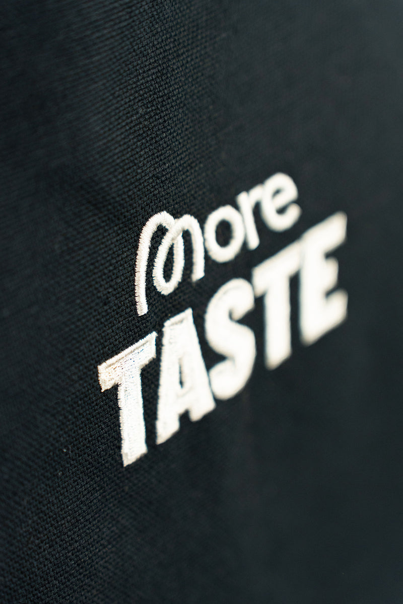 Nahaufnahme der Viskose-Stickerei auf der schwarzen More Taste Schürze