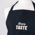 Helle More Taste Stickerei auf der schwarzen Schürze