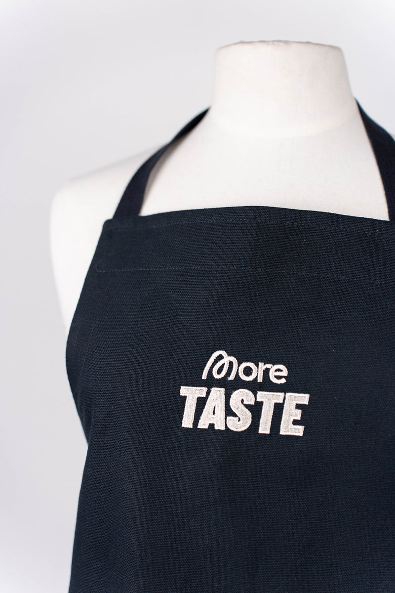 Helle More Taste Stickerei auf der schwarzen Schürze